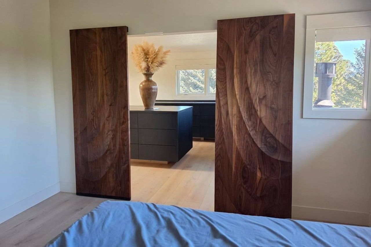 Pair of solid walnut sliding doors carved in sweeping relief, opening onto a dressing room — walnut, custom commission